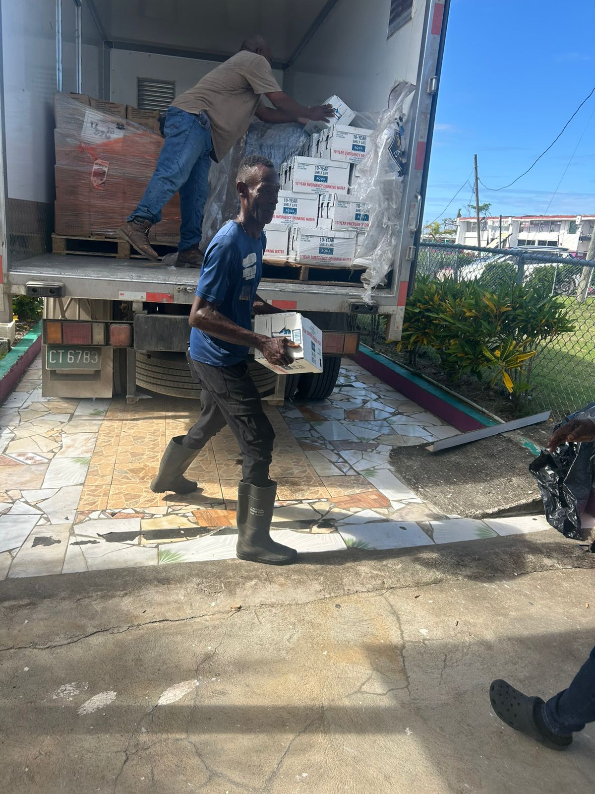 Workmen unload pallets of water and meals ready to eat donated through Olympian Claston Bernard